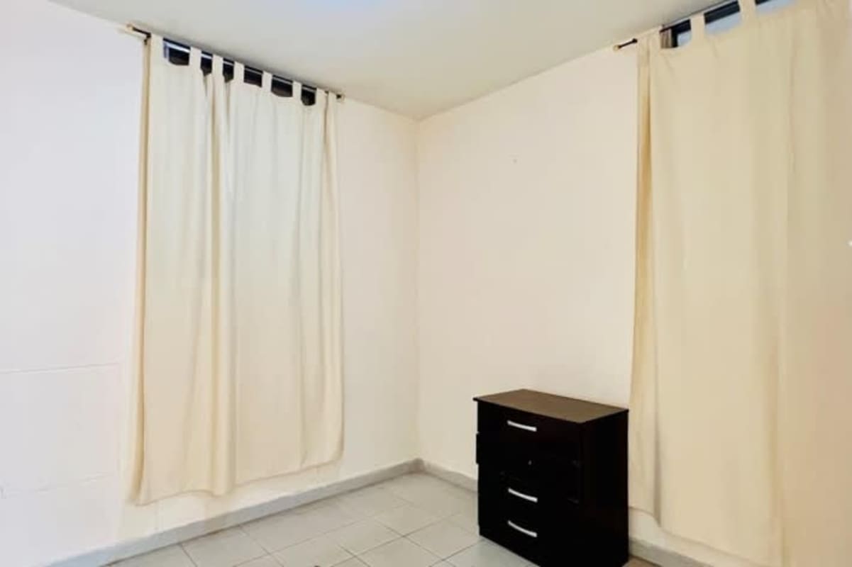 Minimalist bedroom with two windows covered, tiled floor, black nightstand in apartment rental