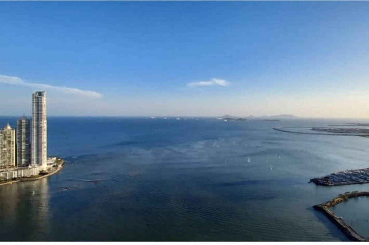 Open plan kitchen in PH BICSA luxury apartment featuring island, stainless appliances, bright dining space