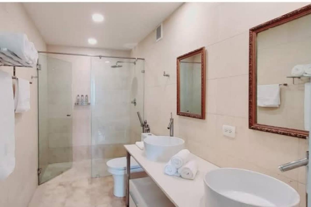 Designer bathroom in luxury apartment at PH BICSA featuring double sinks and glass shower enclosure