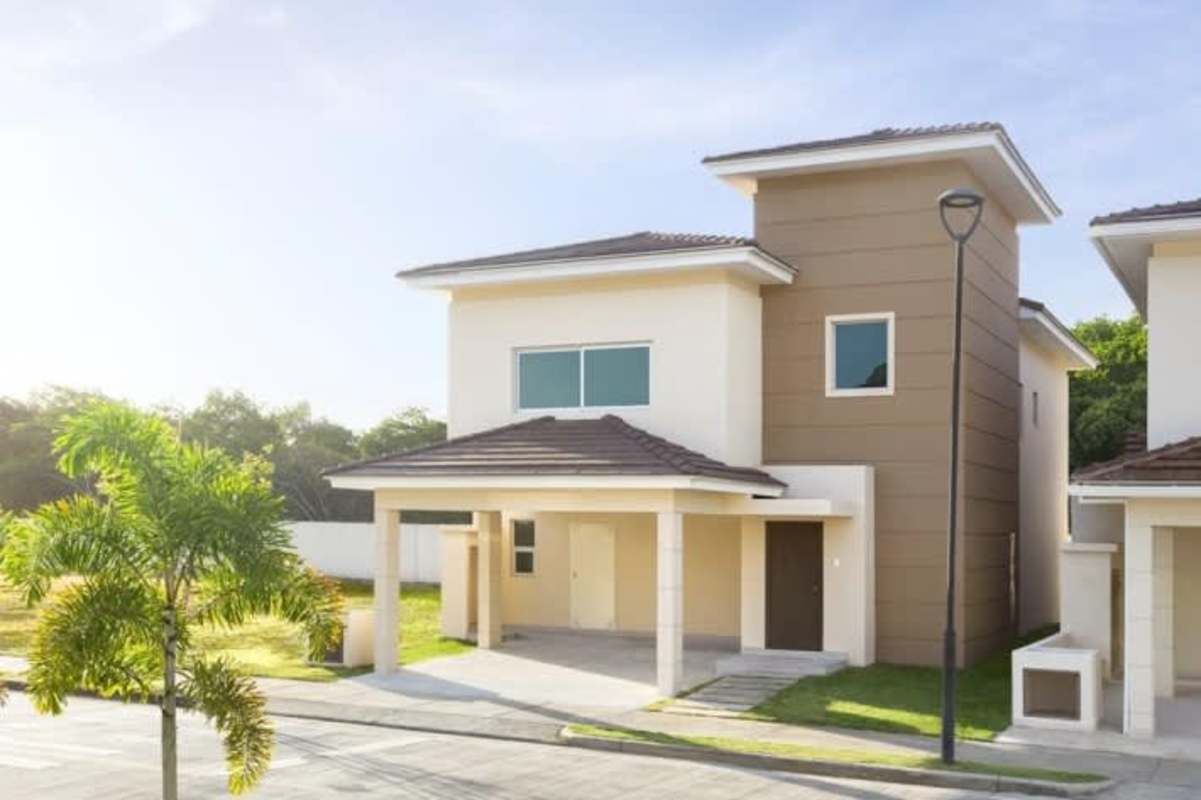 Contemporary two-story house exterior with minimalist cream facade and carport in Altos del Parque Ancon Panama