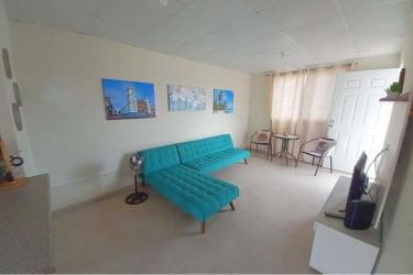 Modern minimalist living room with teal sofa, dining area and TV stand in Penonomé