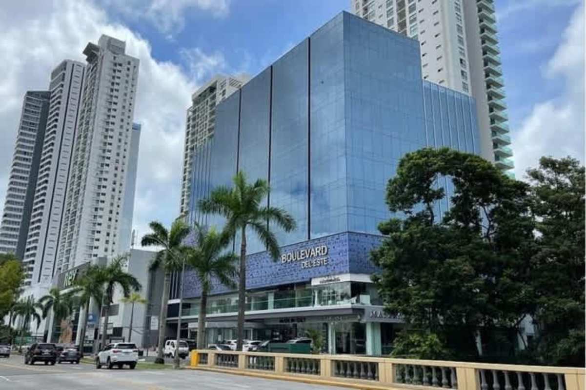 Modern glass-fronted commercial building ‘Boulevard del Este’ in Costa del Este Panama with palm trees and busy avenue