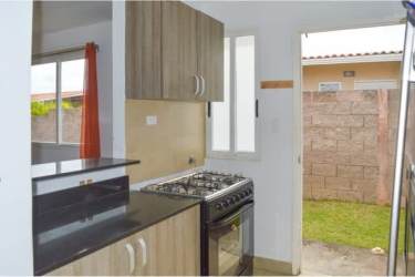 Modern compact kitchen with wood cabinets, granite countertop and door to backyard Coronado Panama