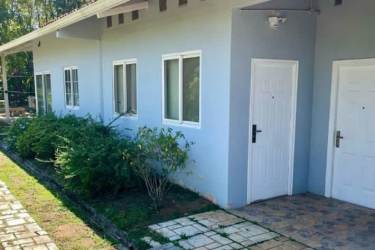 White one-story house with stone walkway lush greenery riverside retreat Panama