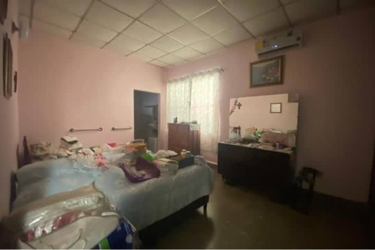 Bedroom with large window security bars, wall-length closet and tiled floor in Rio Abajo family house for sale