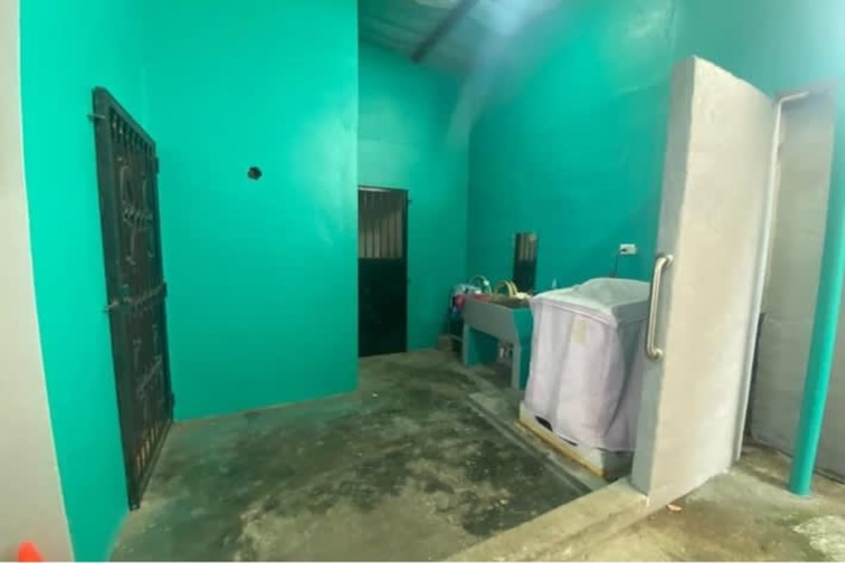 Simple laundry space with cement floor, turquoise wall, utility sink in Rio Abajo Panama