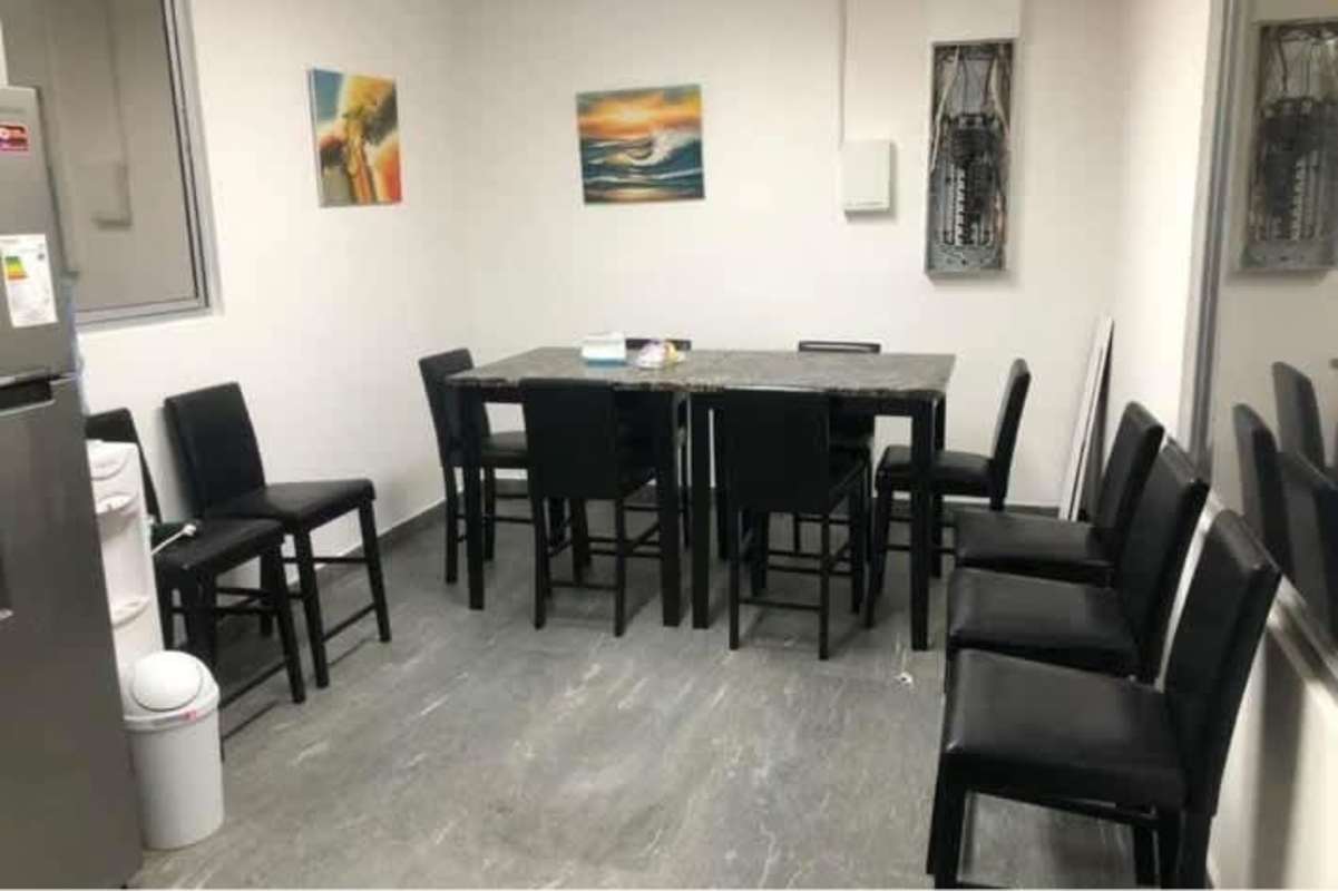 Dining break room with marble table, black chairs, appliances inside Costa del Este office
