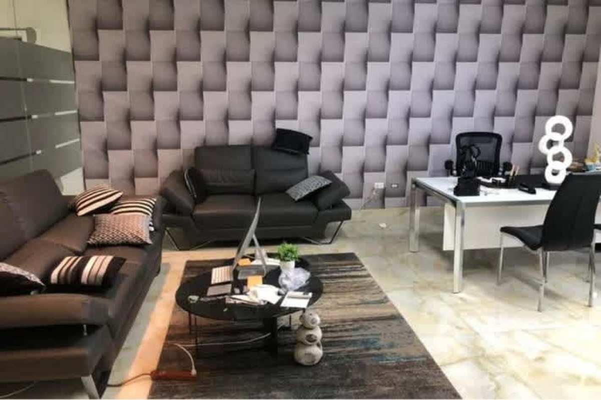 Office lounge area with black sofas, marble floor, geometric wall at Parque Industrial Costa del Este