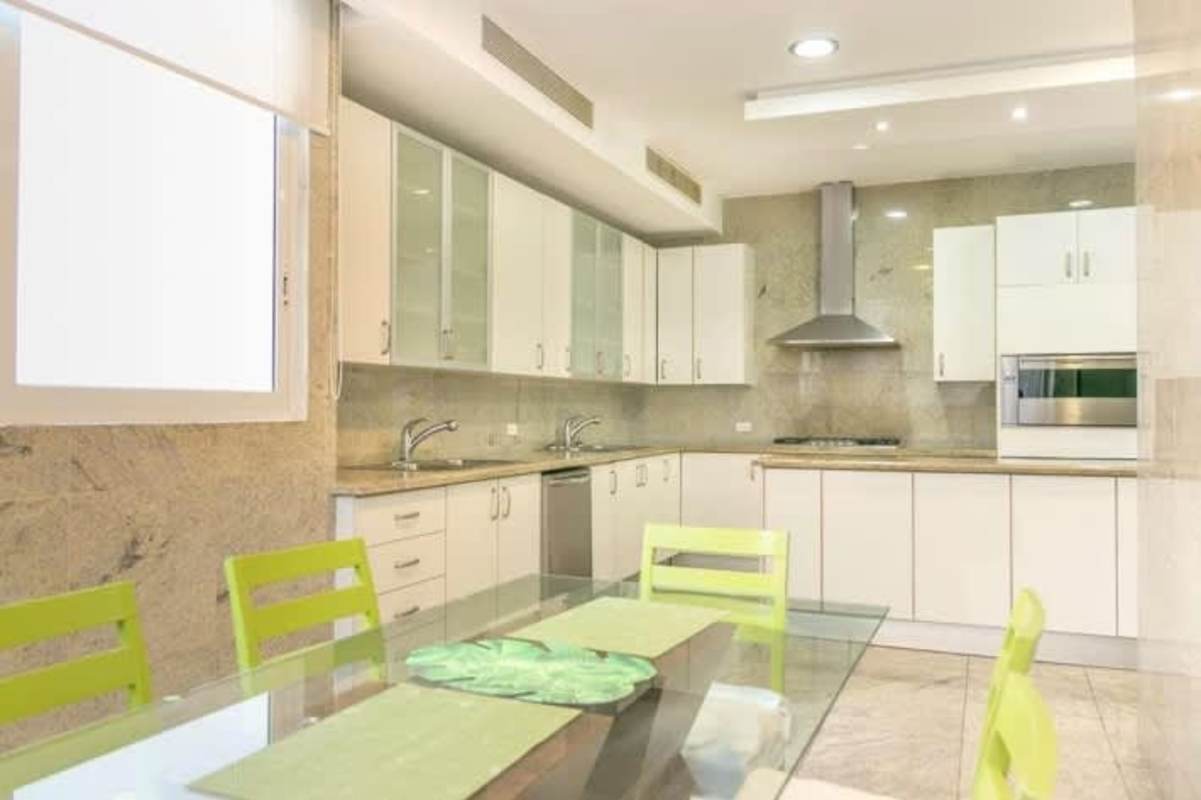 Spacious kitchen with glass cabinet doors, marble backsplash, and stainless appliances at PH Miradores Panama