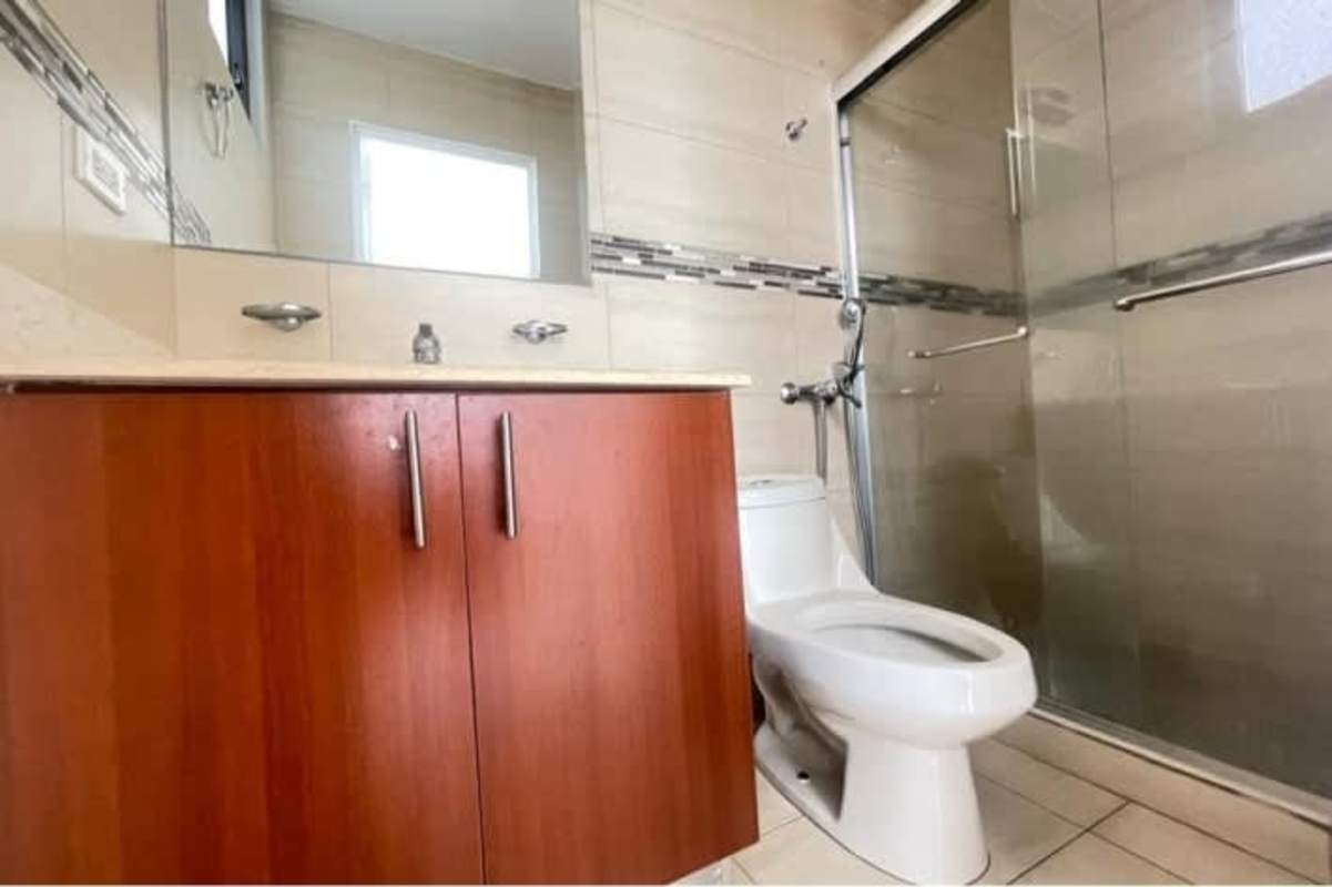 Modern bathroom with pedestal sink, glass shower enclosure, and elegant tiles in PH Vía Romana Panama City