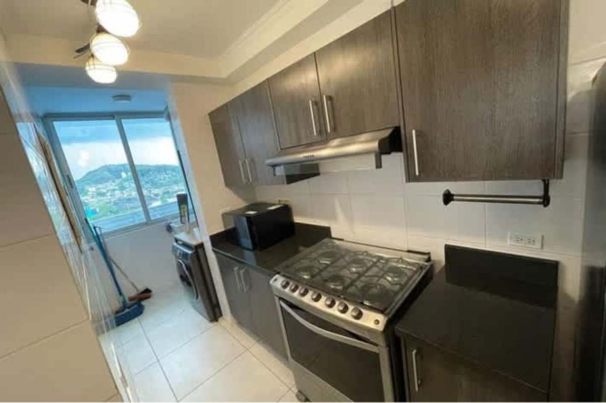 Contemporary kitchen with dark cabinetry, gas stove, microwave, and washer unit PH Sky Point Towers Panama City
