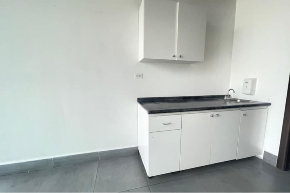 Compact kitchenette with white cabinets and black countertop in PH BICSA commercial office