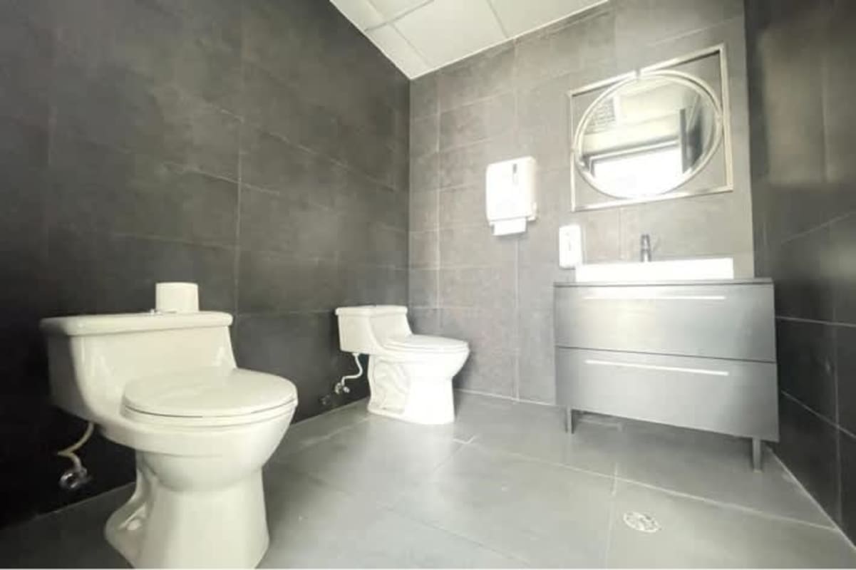 Double stall restroom with modern fixtures and dark tile in PH BICSA commercial tower Panama City