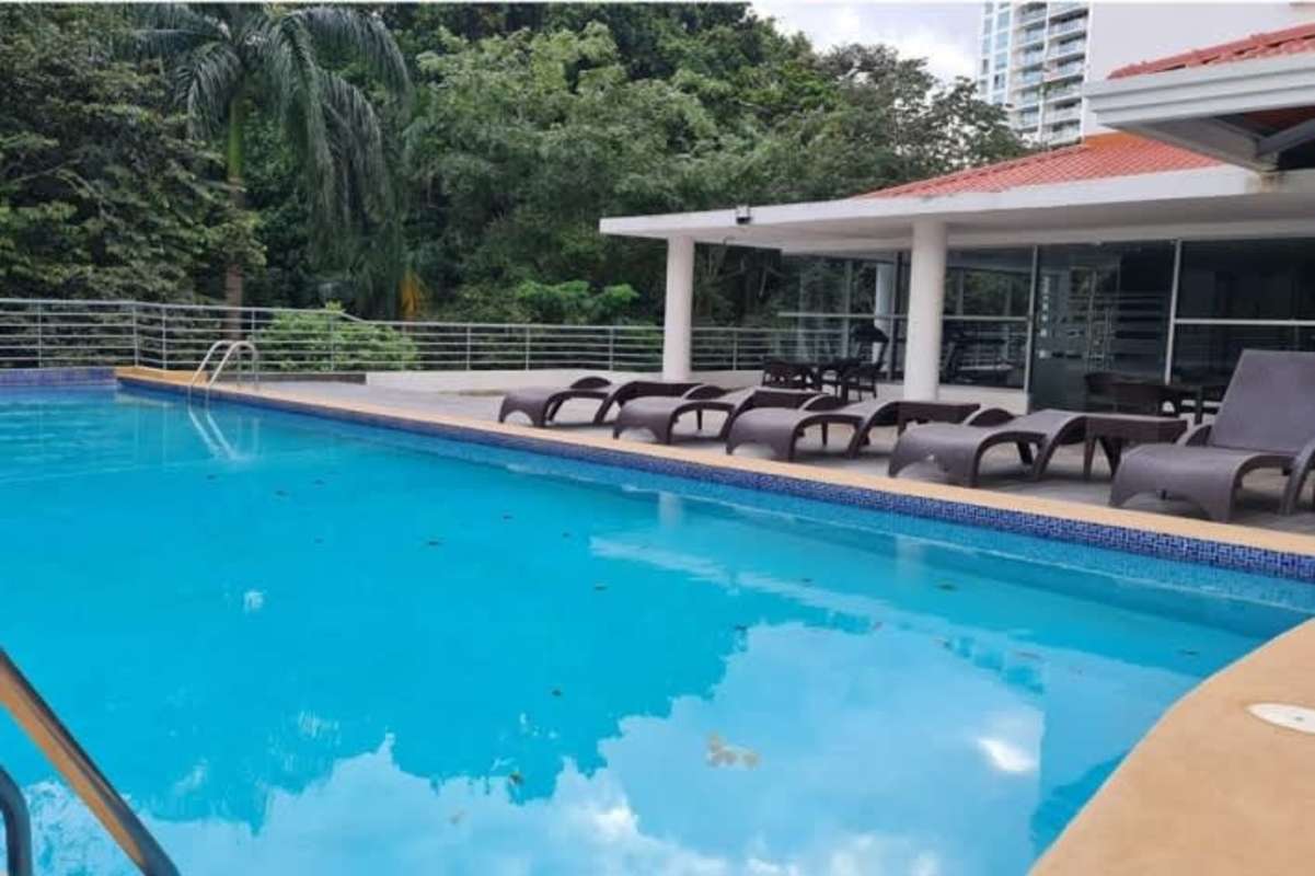 Pool area with lounge chairs and covered social space at PH Clayton Park in Panama