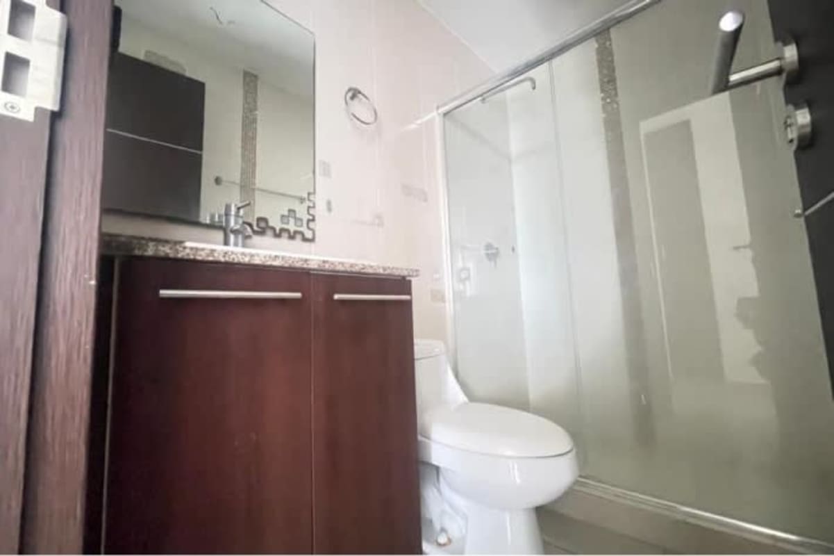 Modern bathroom with glass-enclosed shower, granite vanity, and large mirror Villa de Las Fuentes Panama