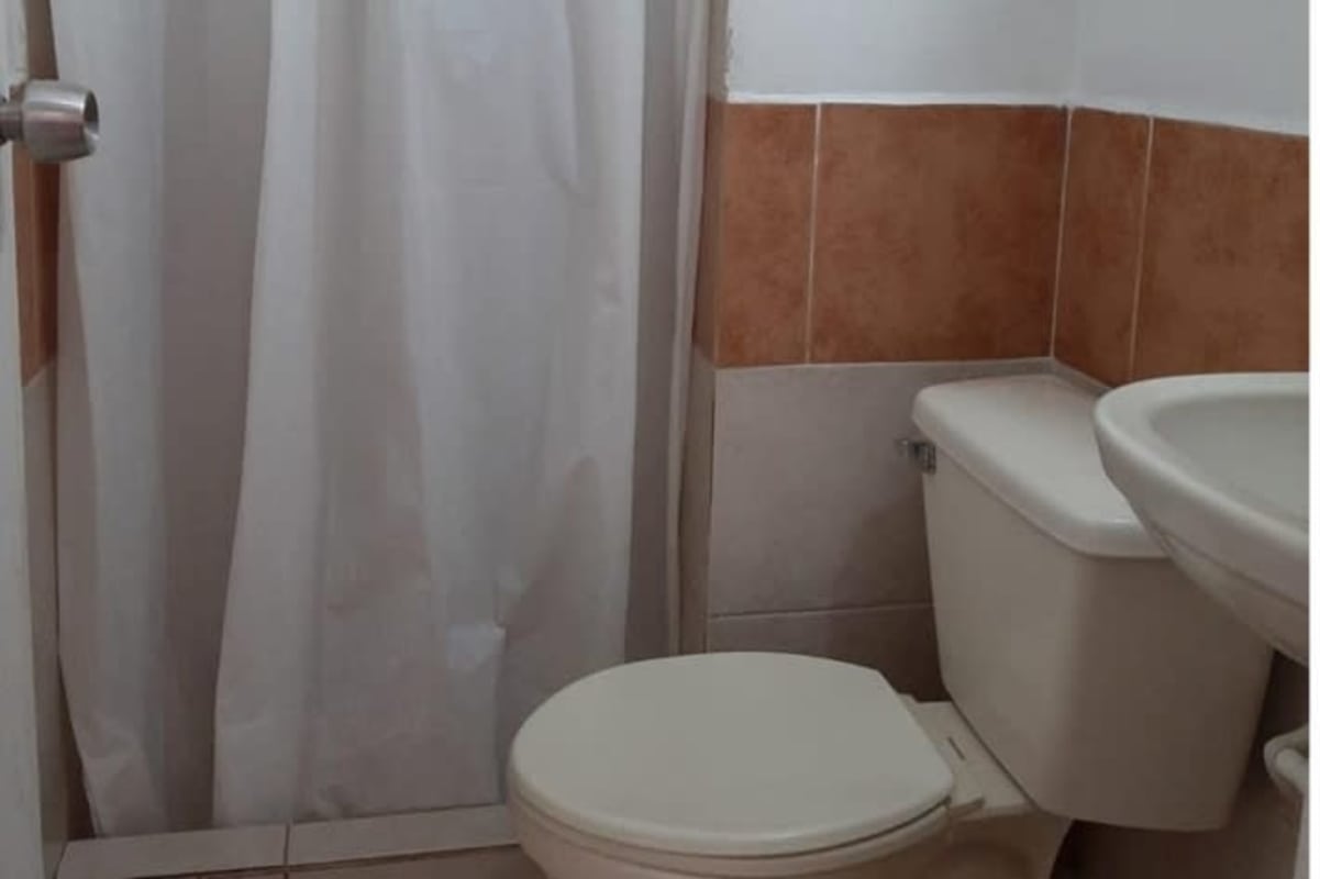 Bathroom with shower curtain, wall sink, tile in budget-friendly condo Juan Díaz Panama