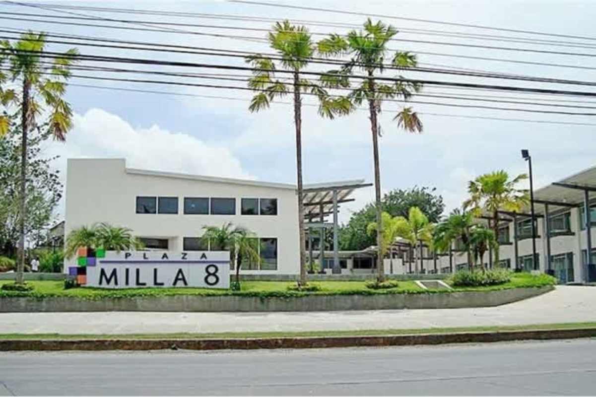 Large empty commercial rental space with red staircase leading to mezzanine level in Plaza Milla 8, Panama.