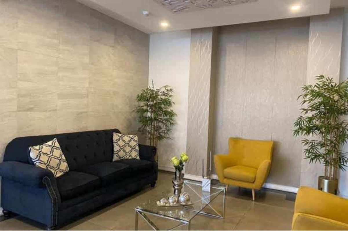 Modern living room with accent walls, blue sofa and yellow armchairs in Marquis Tower apartment