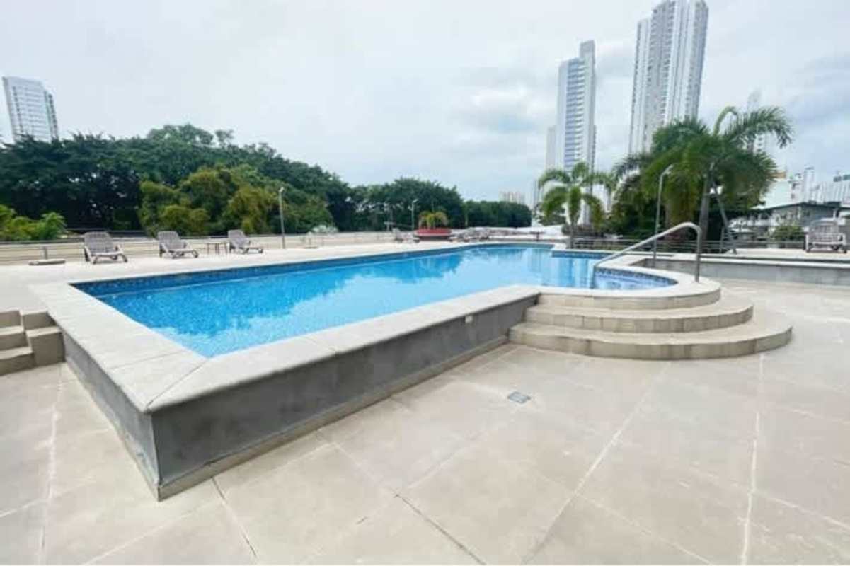 Community swimming pool with deck chairs and skyline view in PH Carrasquilla Park San Francisco Panama