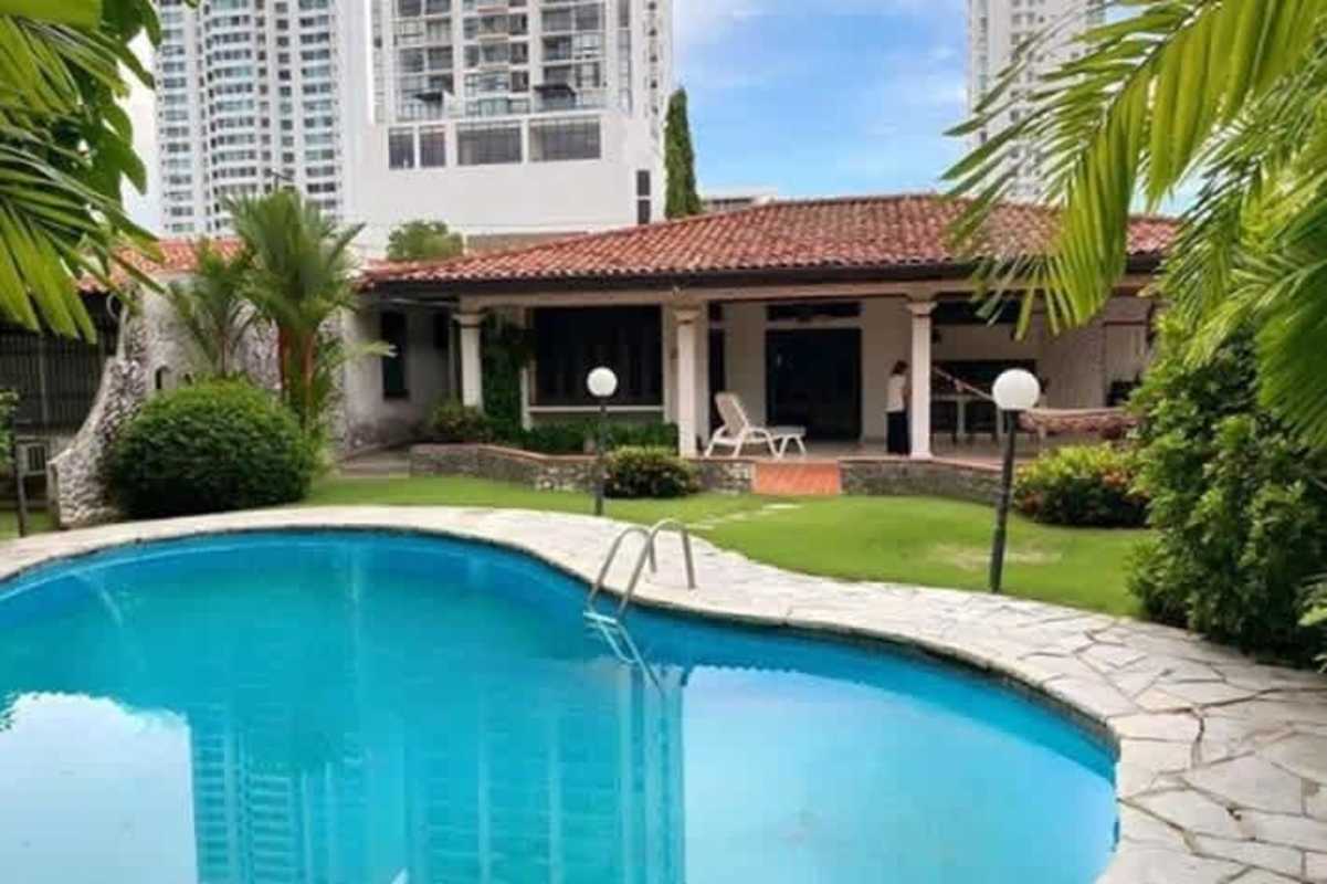 Swimming pool with waterfall, lush garden, and Mediterranean style home in Altos del Golf Panama City