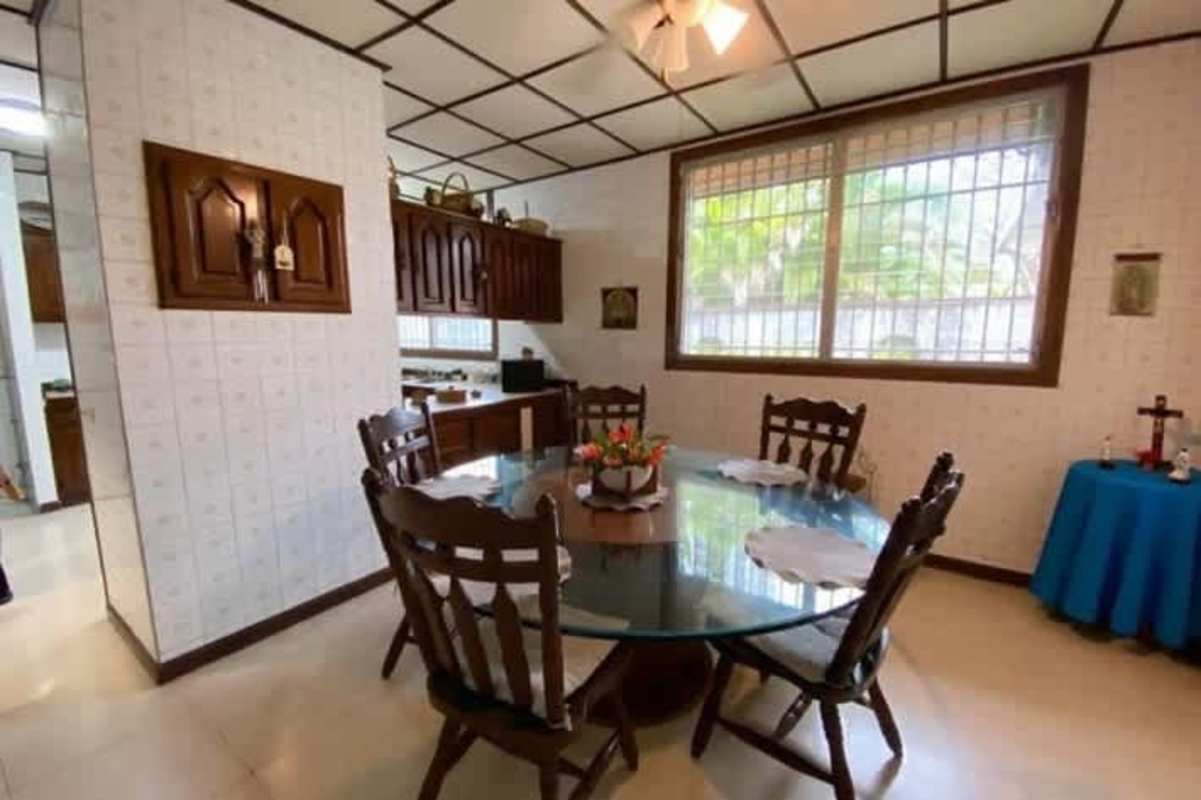 Dining room with glass table, large windows, wood cabinetry, ceiling fan in Panama City house
