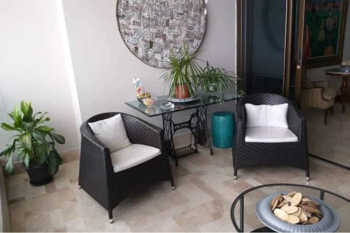 Indoor sunroom with wicker chairs, plants and ocean views PH Oceania Costa del Este