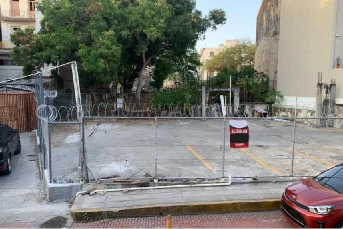 Fenced commercial lot with barbed wire security and neighboring colonial buildings Casco Viejo