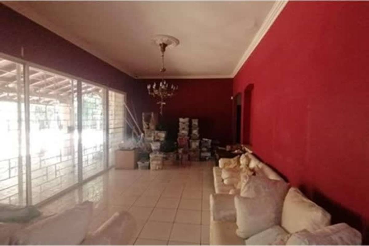 Large living room with red accent wall, sliding glass doors, tiled floor in Las Cumbres Pedregal house Panama City