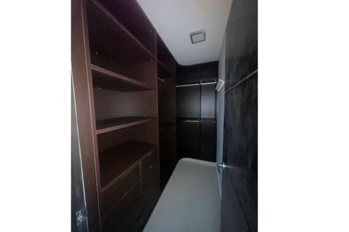 Spacious walk-in closet with built-in storage dark wood at PH Clayton Residence in Clayton Panama City
