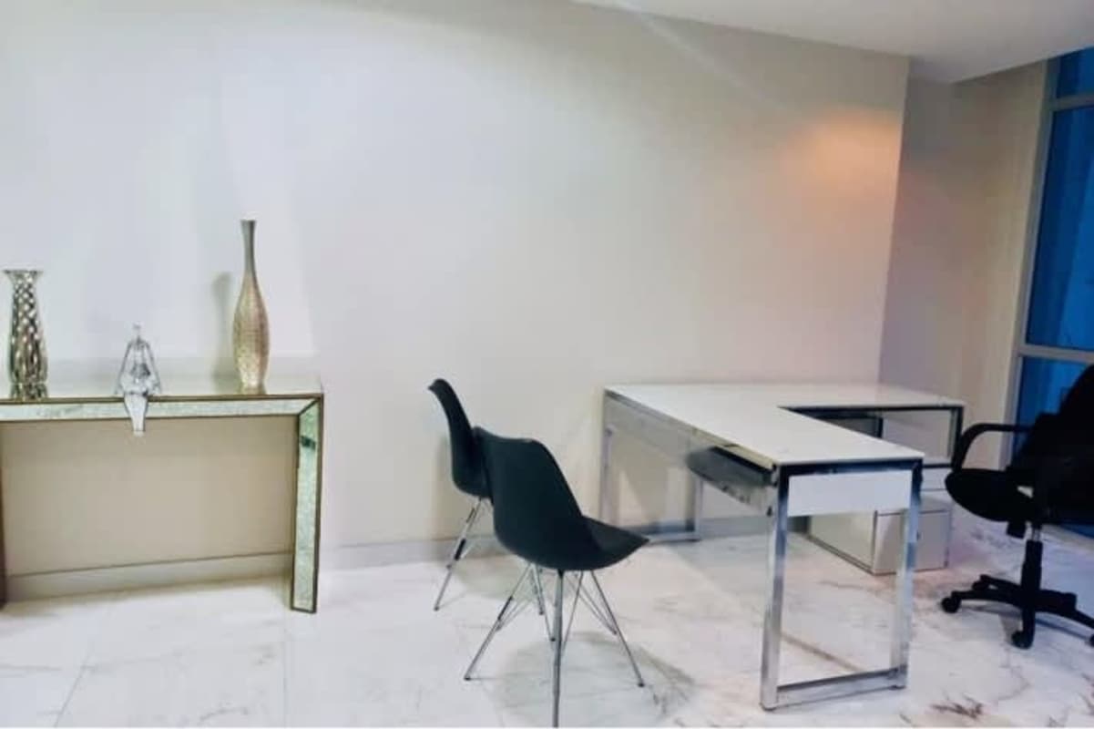 Work area with white walls, marble flooring and large windows overlooking Panama City skyline