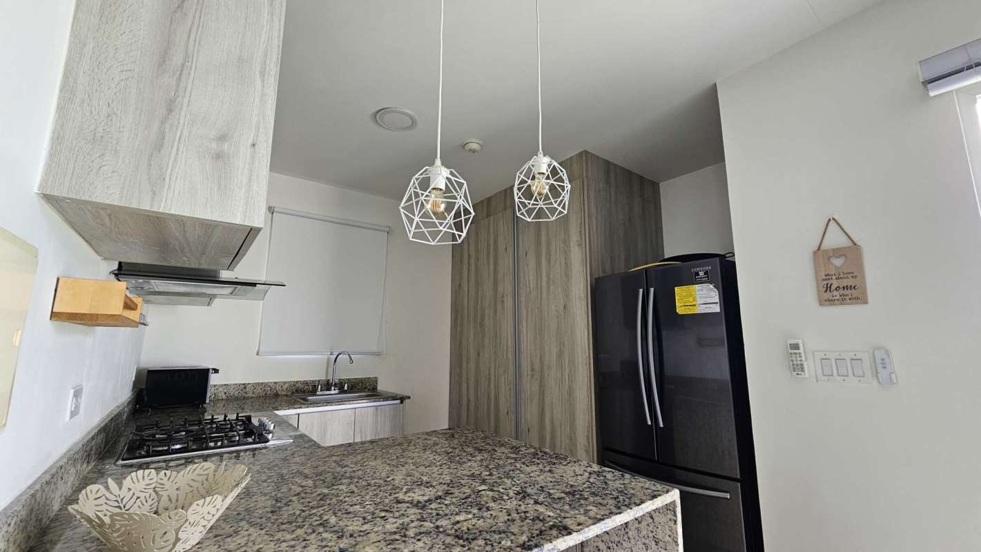 Kitchen in Costa Sur home featuring granite counters, modern cabinets, pendant lighting
