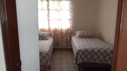 Cozy guest bedroom with two beds and curtains at Coronado vacation house Panama
