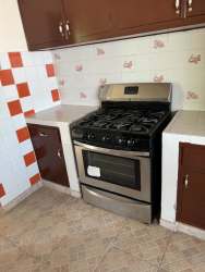 Traditional kitchen white tiles red accents cabinets stainless stove at Coronado beach rental Panama