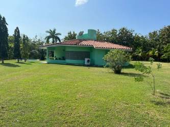 Light green single-story house with terracotta roof large grassy lot in Coronado Panama