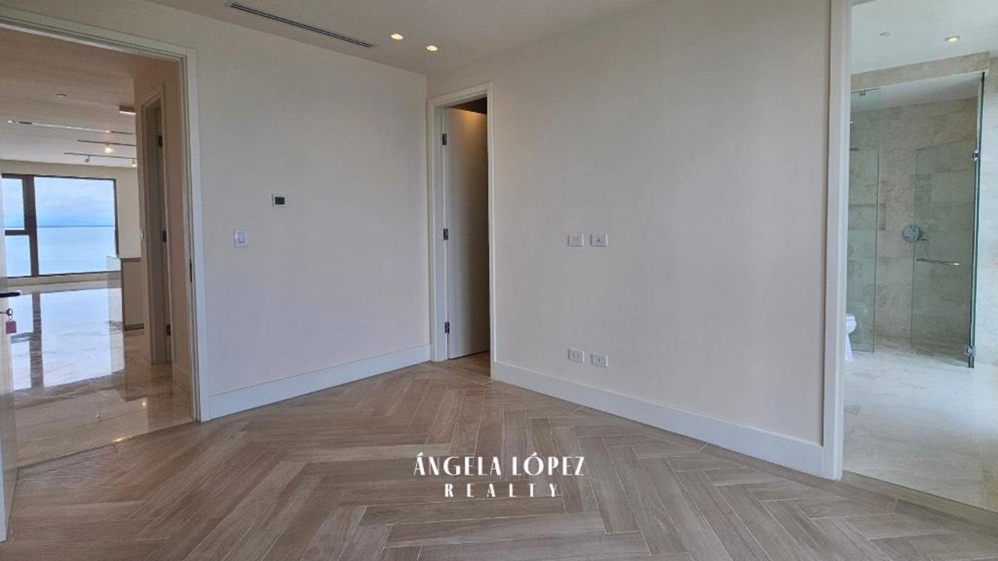 Luxury master bedroom with large window ocean view, herringbone wood flooring, ensuite bathroom at Seascape Ocean Reef Panama