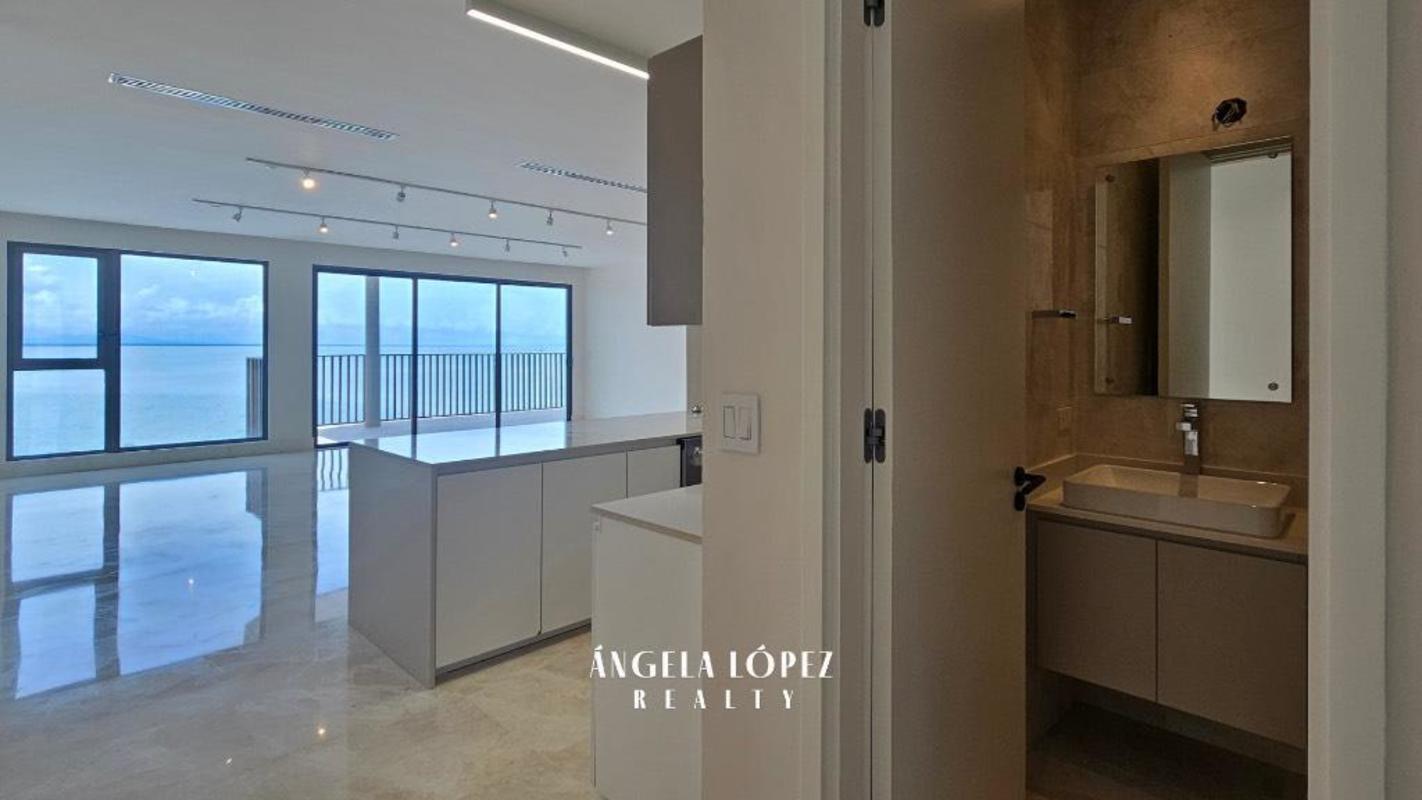 Modern luxury bath with glass shower next to bright ocean-facing living room in Seascape Ocean Reef Panama