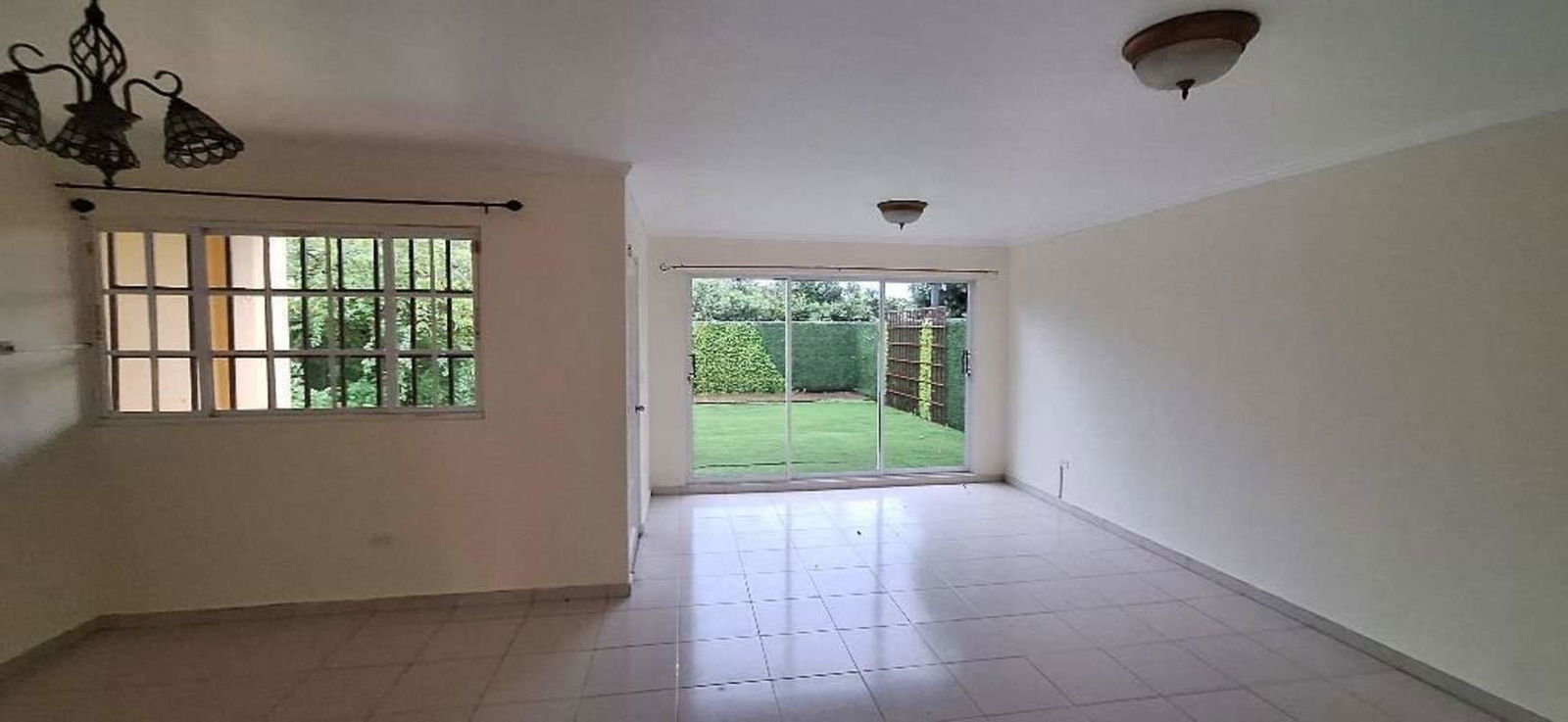 Spacious green backyard with lawn, hedge fence and covered patio in Villa Zaita house for sale