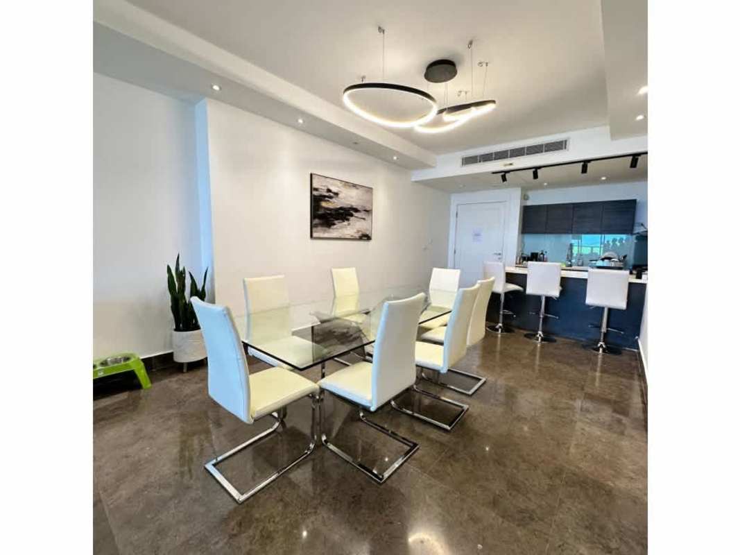 Modern open dining and kitchen with bar seating, pendant lighting at luxury Panama condo