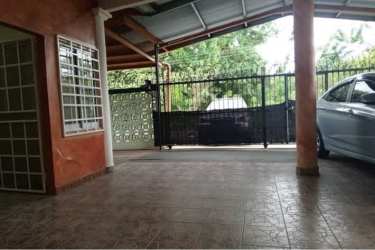 Covered parking with tiled floor and metal gate beside house Villa Dora 2 David Chiriquí Panama