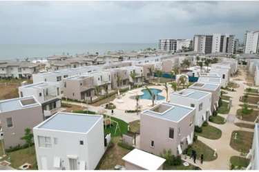 Bright coastal modern living room with sliding glass door to balcony overlooking gardens at Costa Chame Panama