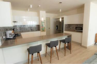 Open kitchen with island adjacent to bright living area at Costeira Beach Club condo Chame