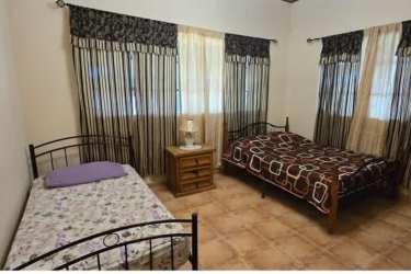 Bedroom with two beds, curtained window and nightstand in Coronado Beach house Panama