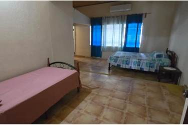 Bedroom with patterned bed linen, open closet and barred windows in Coronado house Panama