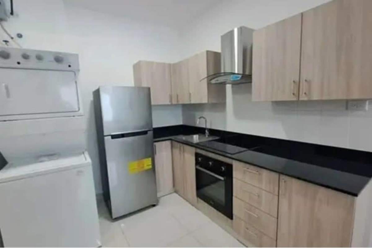 Kitchen with wood cabinets, black granite countertops, washer-dryer unit, fridge, oven and hood in PH Centro del Este Panama City