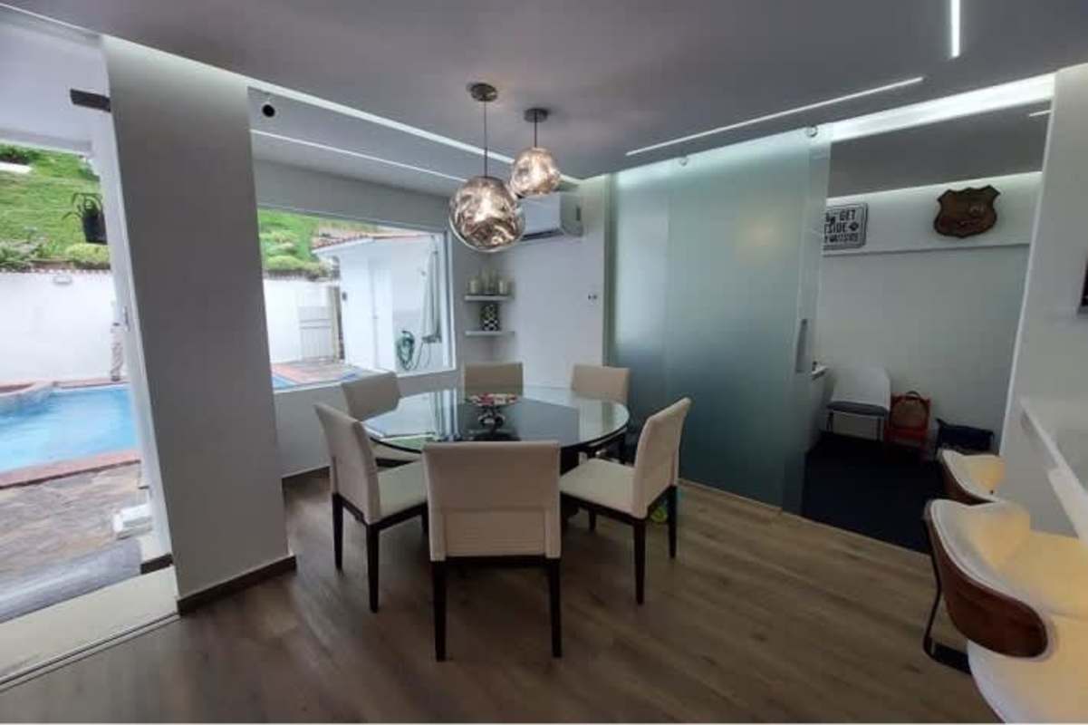 Dining area with glass doors to pool, modern lighting, Green Valley house Panama