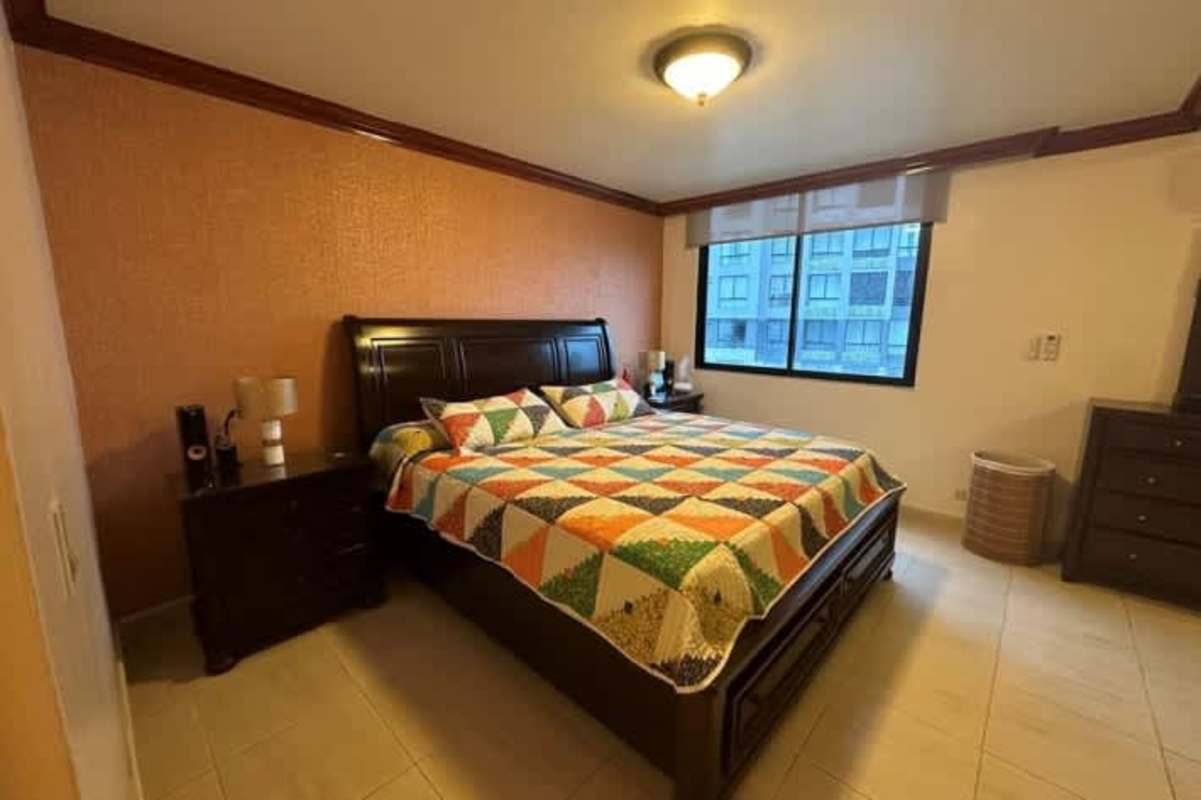 Large bedroom with king bed, city view window, and colorful quilt in PH Bahia Azul Panama City