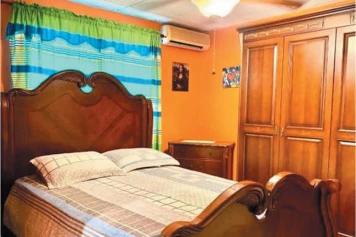 Bedroom with wooden bed, air conditioning, wardrobe in house for sale Las Cumbres Panama