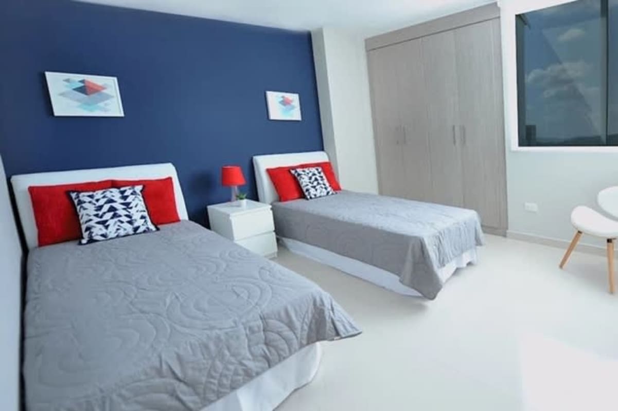Twin bedroom with navy blue accent wall, wardrobes and large window PH Mei Tower Panama