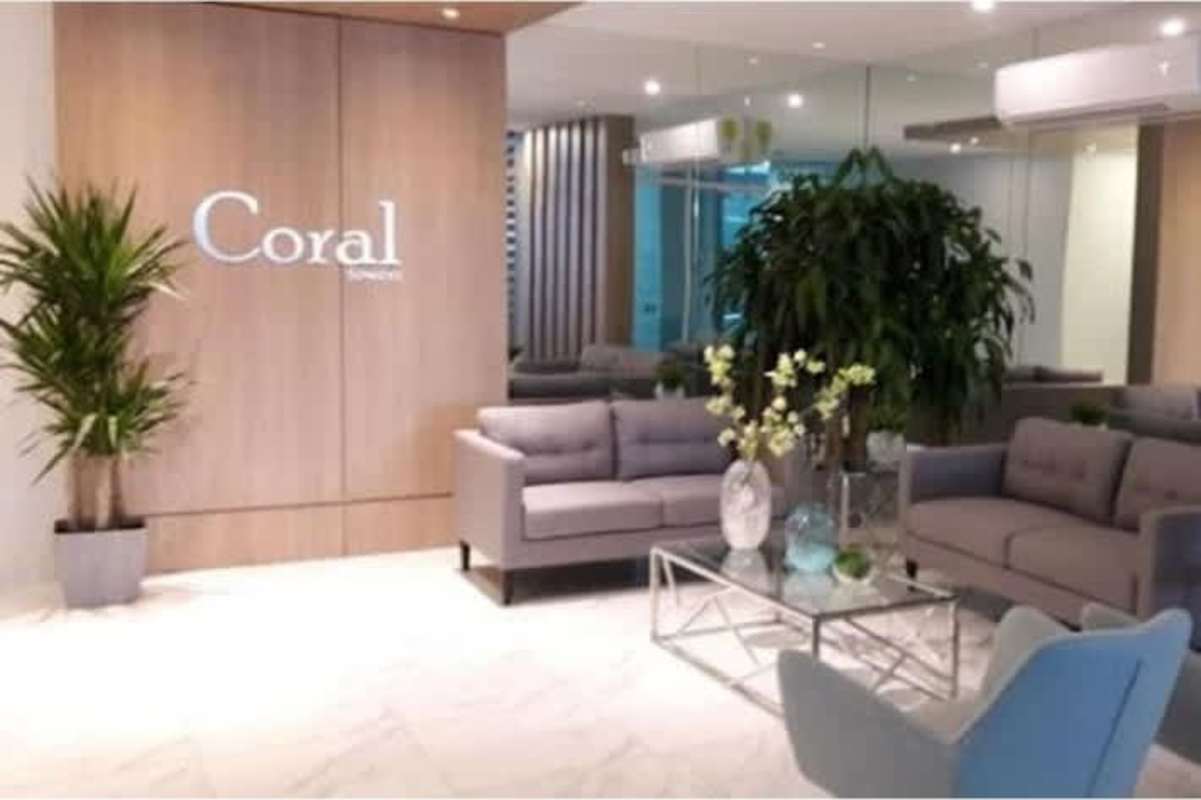 Reception lounge with grey sofas, glass table and decorative plants in PH Coral Towers Parque Lefevre