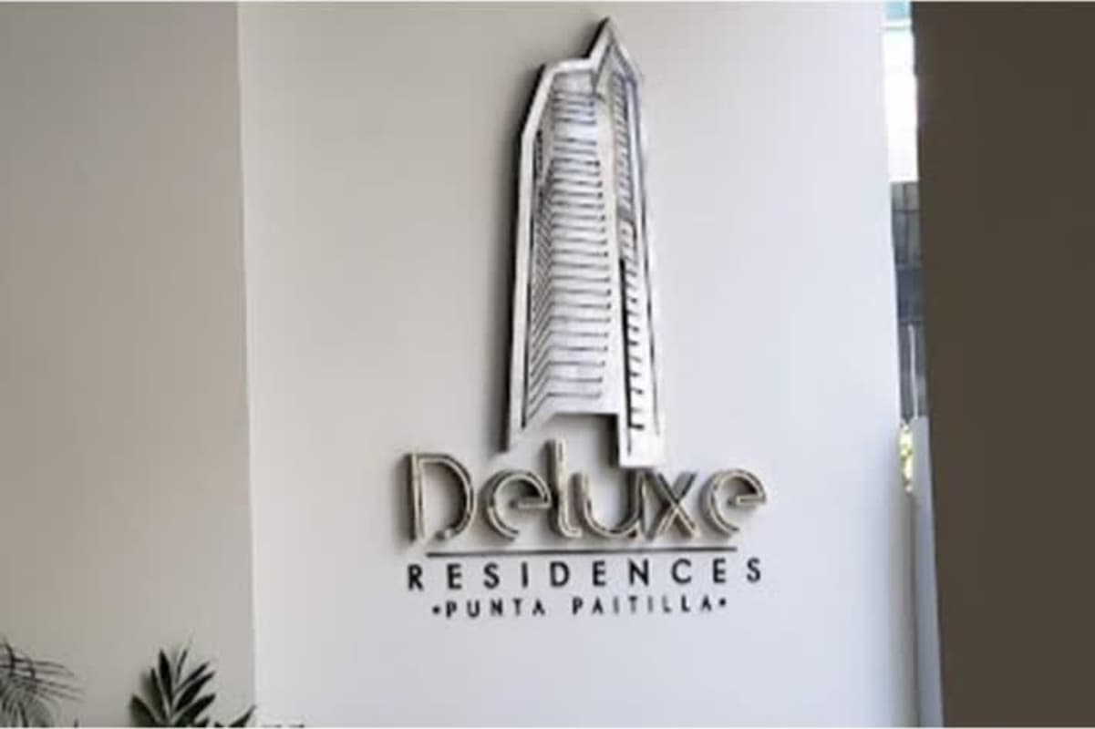 Luxurious condominium with glass facade, grand covered entrance, and city skyline reflections in Punta Paitilla